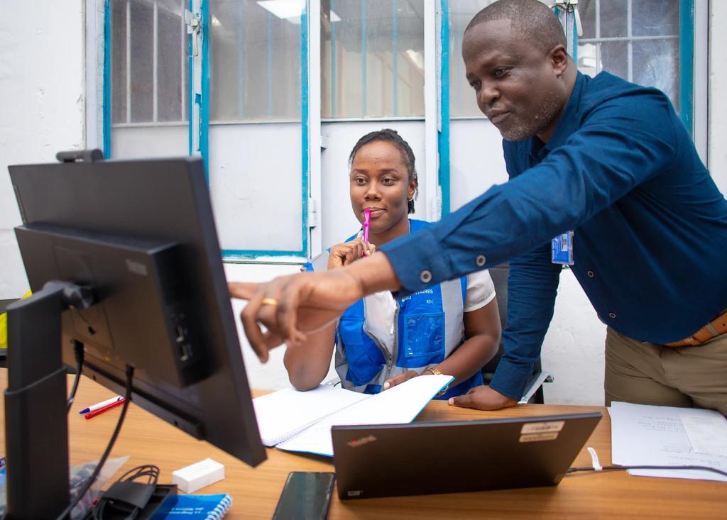 Two UN volunteers work at a computer.