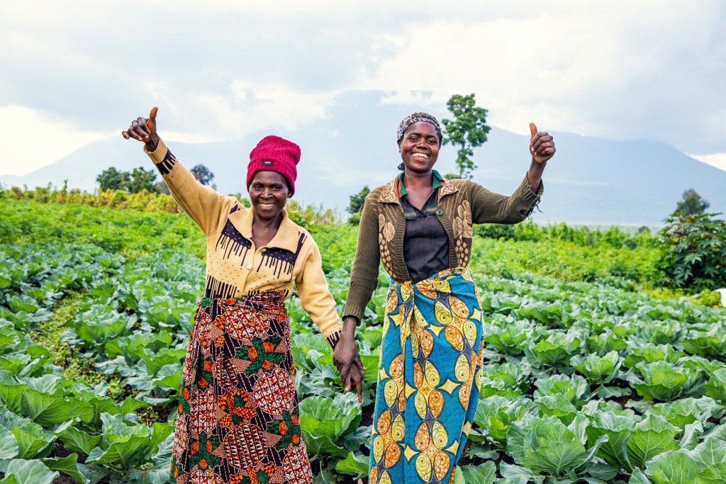 Two women farmers in South Africa stand in a field.