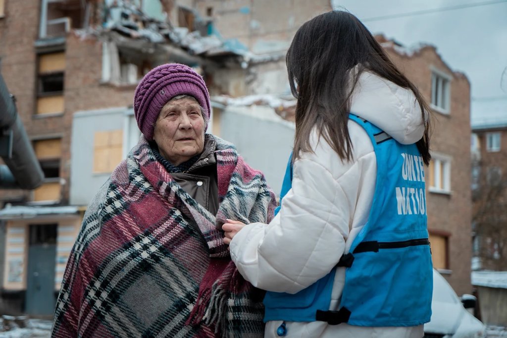 An elderly woman in Ukraine talks to a UN personnel member. 