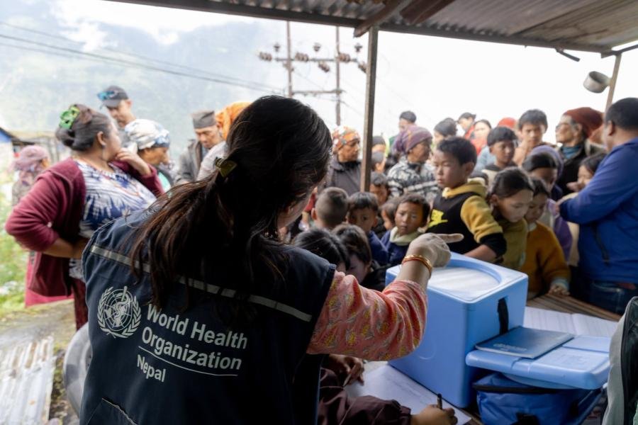 An aid worker distributes supplies following floods in Nepal.
