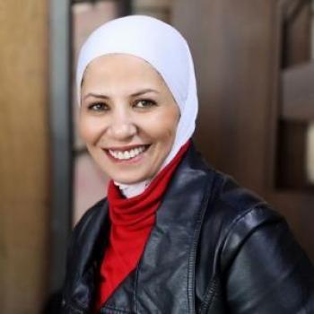A woman wearing a white head scarf and a red shirt.
