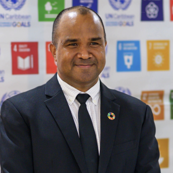 A man stands in front of the United Nations SDG logos. 