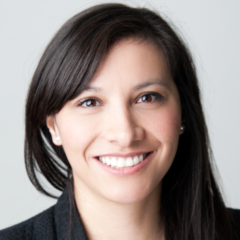 A woman with brown hair smiles brightly at the camera. 