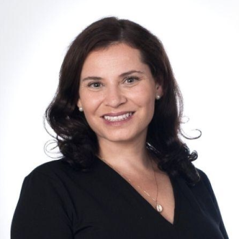 A woman in a black dress smiles at the camera. 