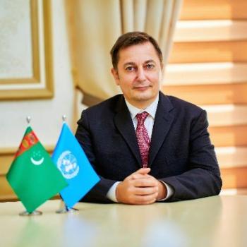 A man sits at a table with two small flags.