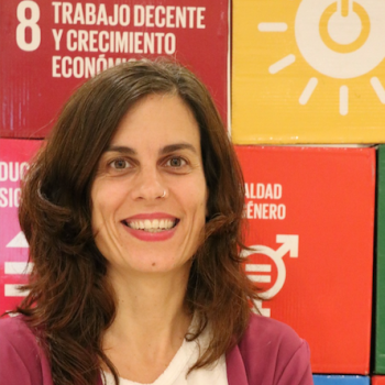 woman with brown hair standing in front of colourful background