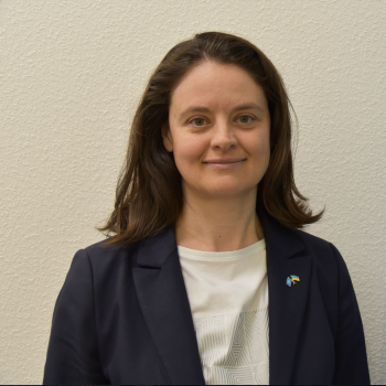 Head of the Resident Coordinator's Office wearing a black blazer standing in front of a background