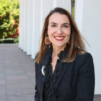 A woman in a black blazer looks at the camera and smiles 