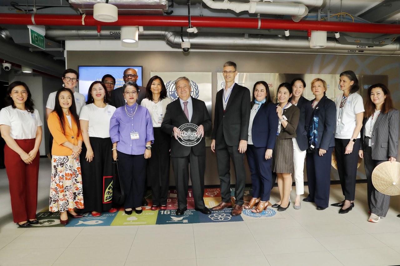 group of people stand posing for a photo with a man in the centre holding an award 