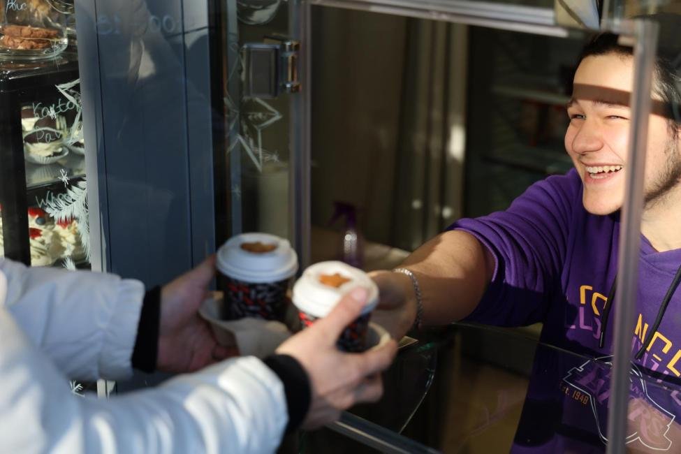 young man serves coffee through a window 