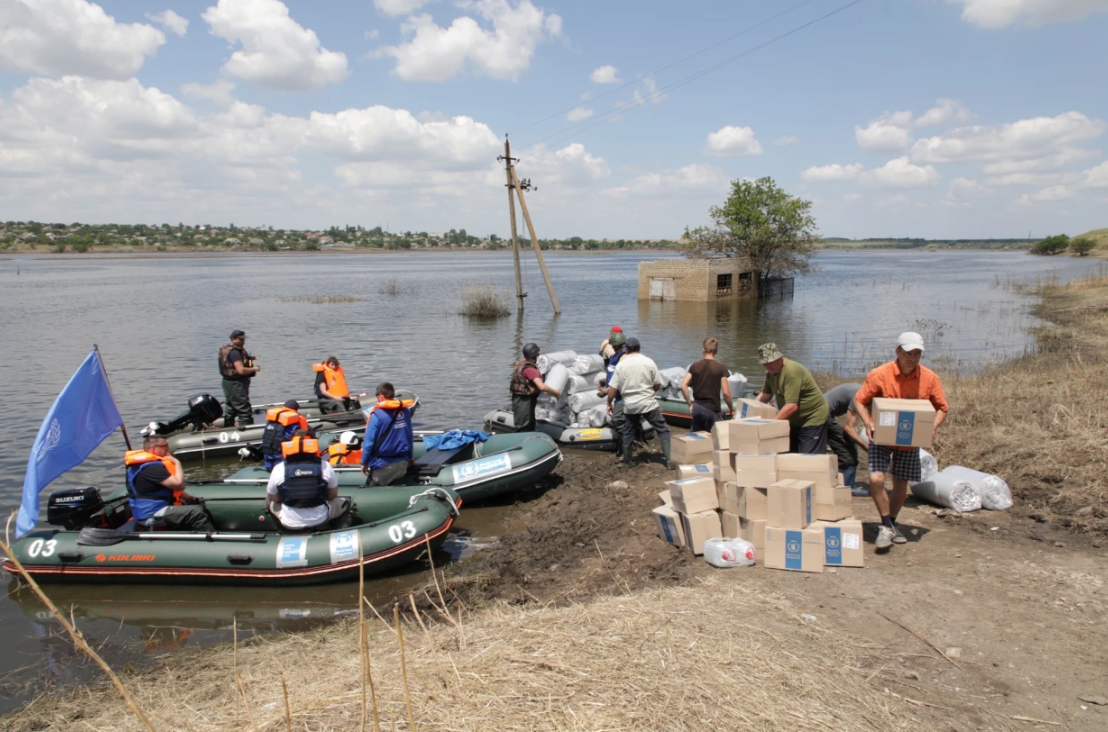 three rubber boats offloading aid at the river bank