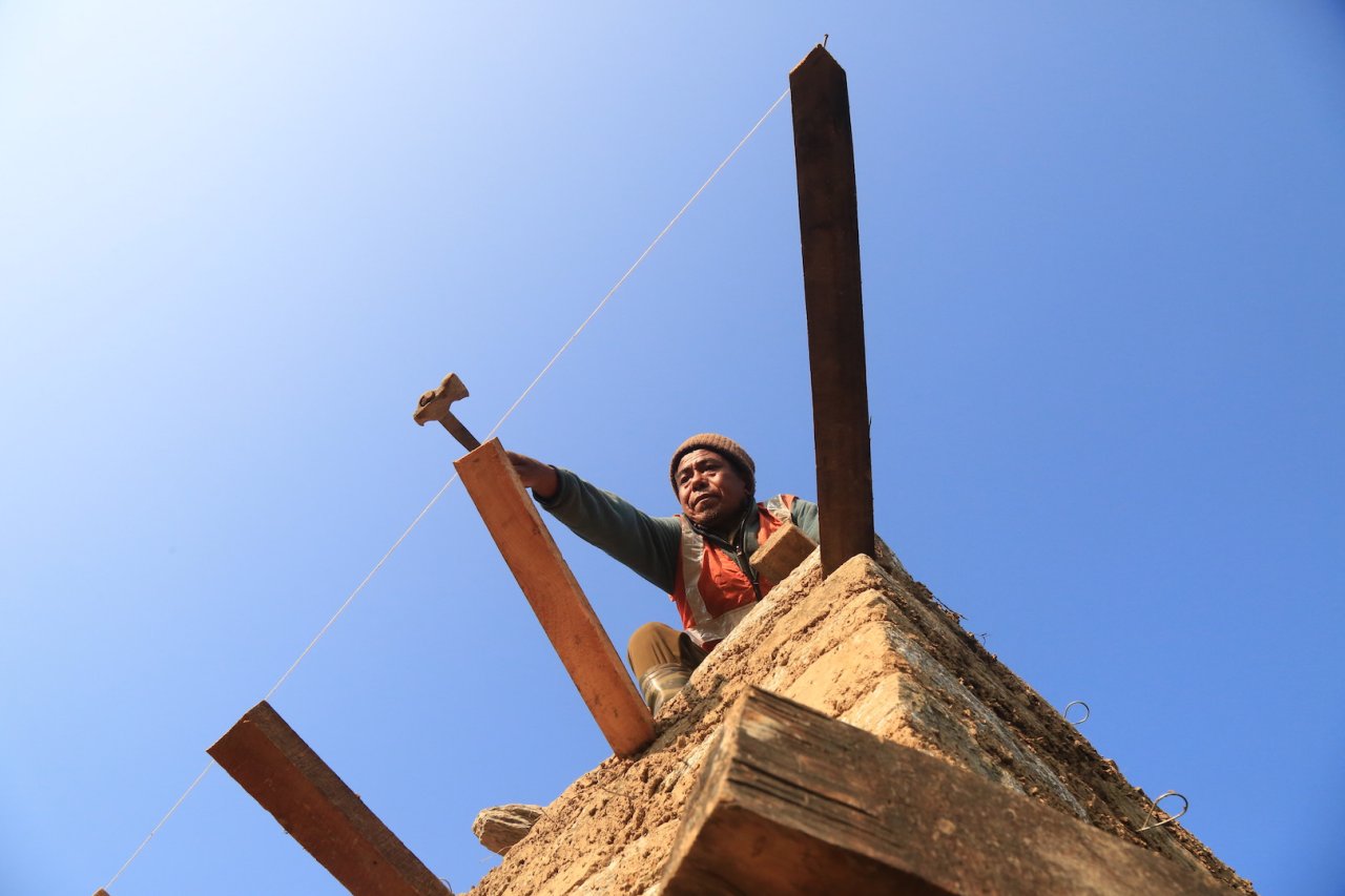 photo looking up to a man who is working on wooden structure 