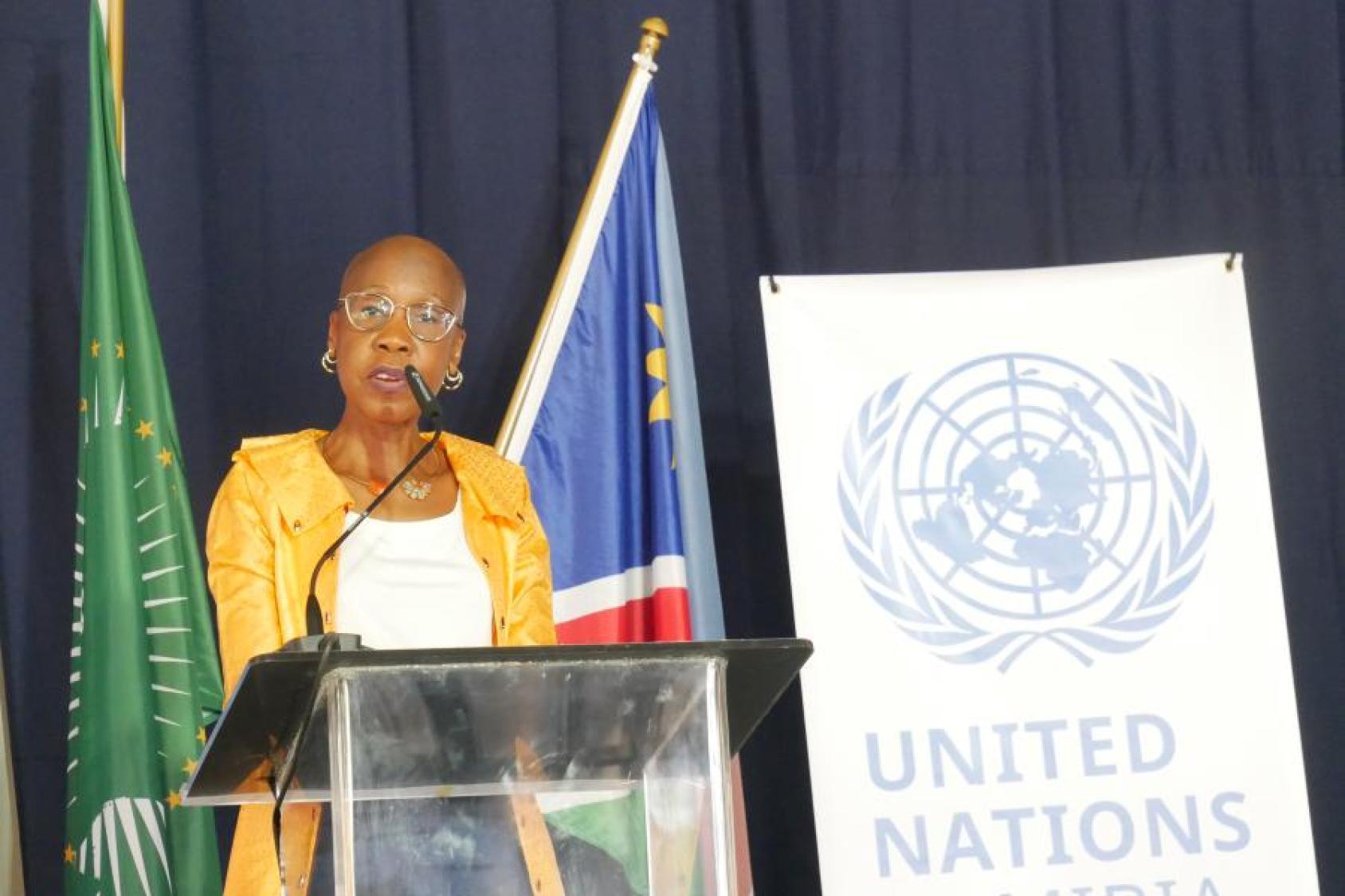 A woman in a yellow dress stands at the podium