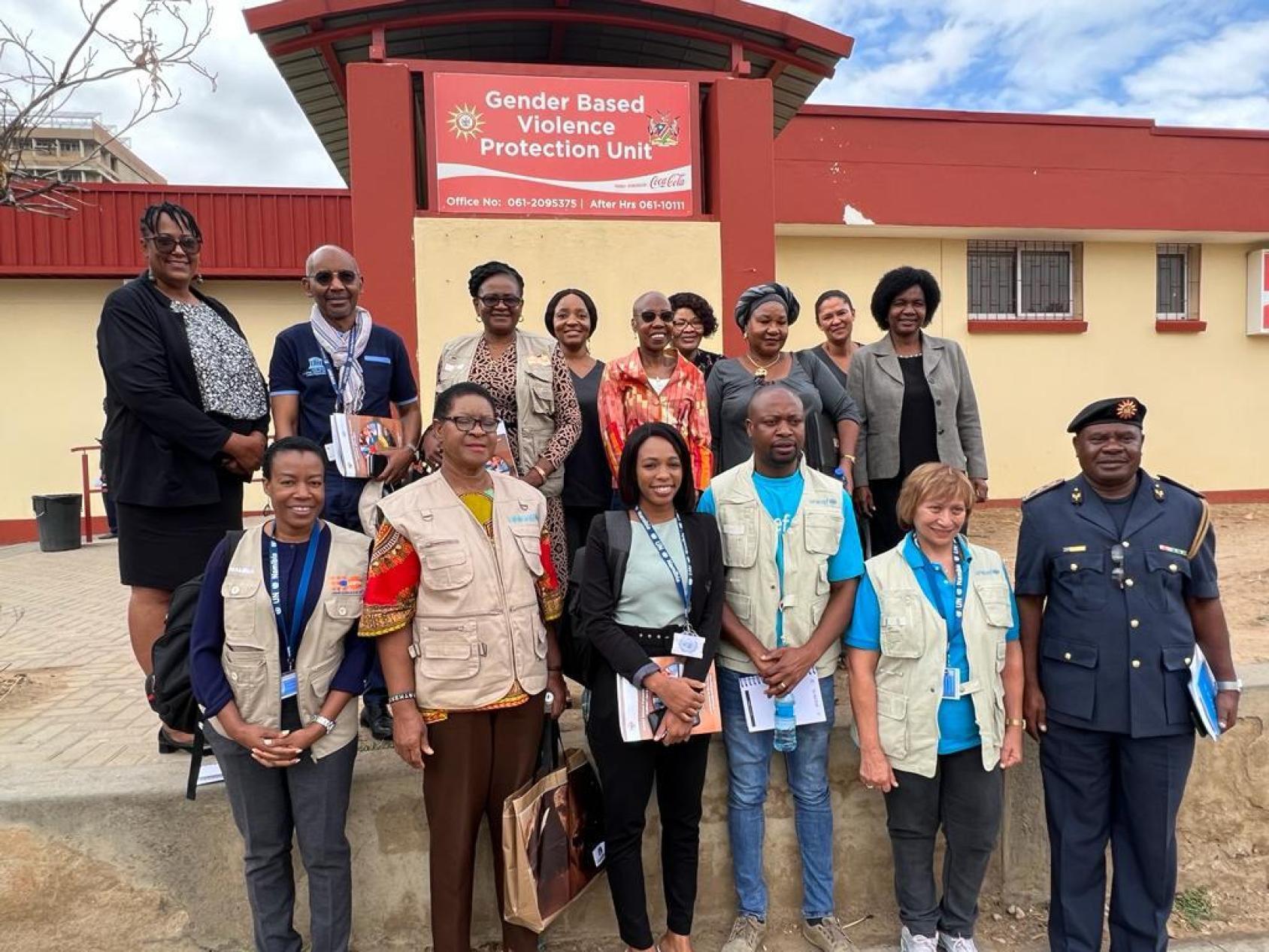 A group of people on a field visit posing in front of a building in an outdoor setting