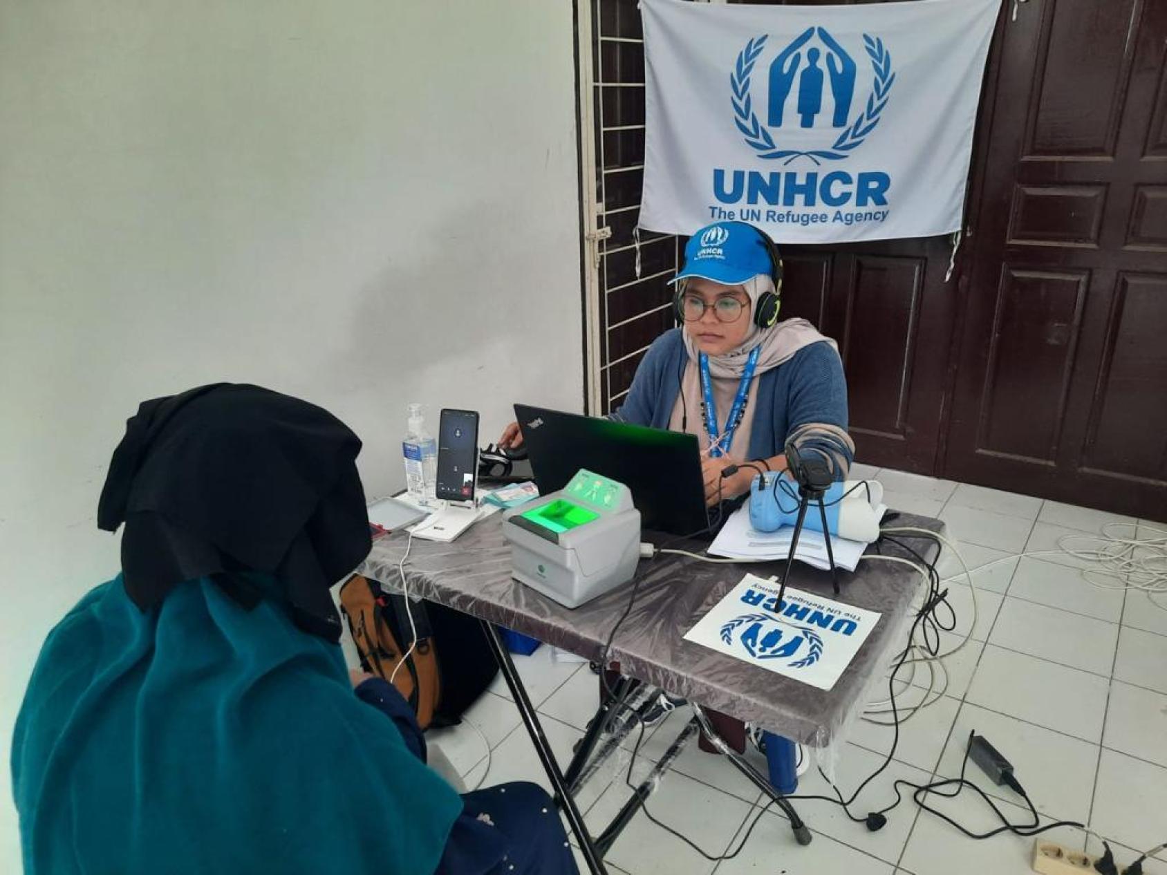 A woman in a blue cap sits in front of a woman interviewing another woman