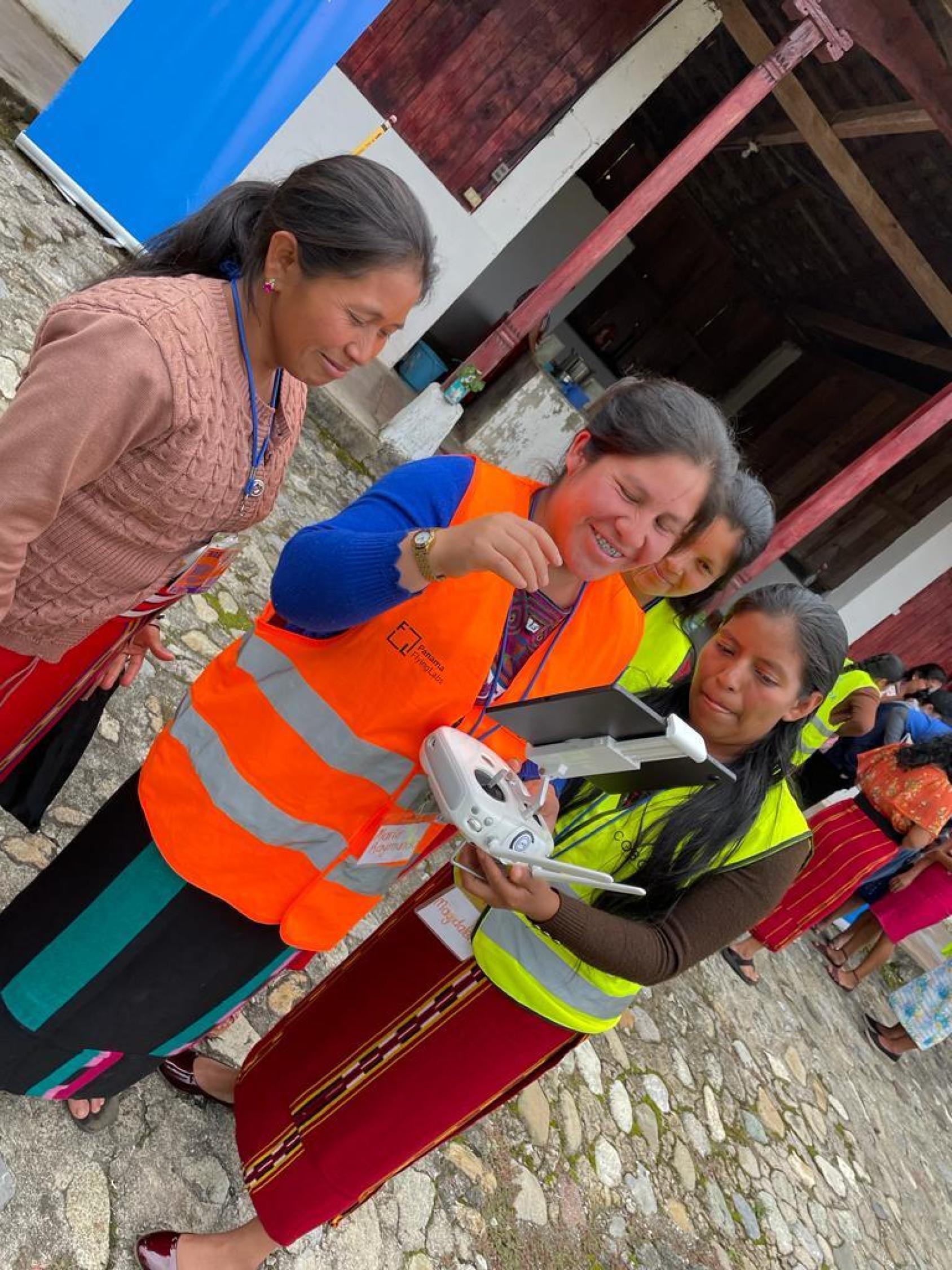 A woman is learning to fly a drone as her friends look on