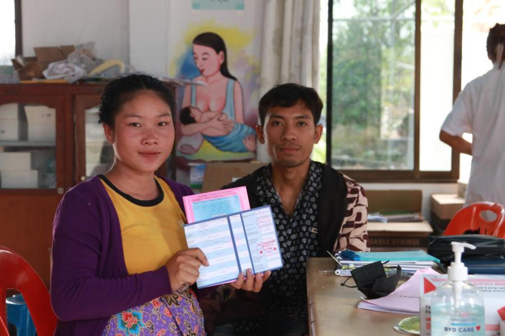 Two people look at the camera holding a government document