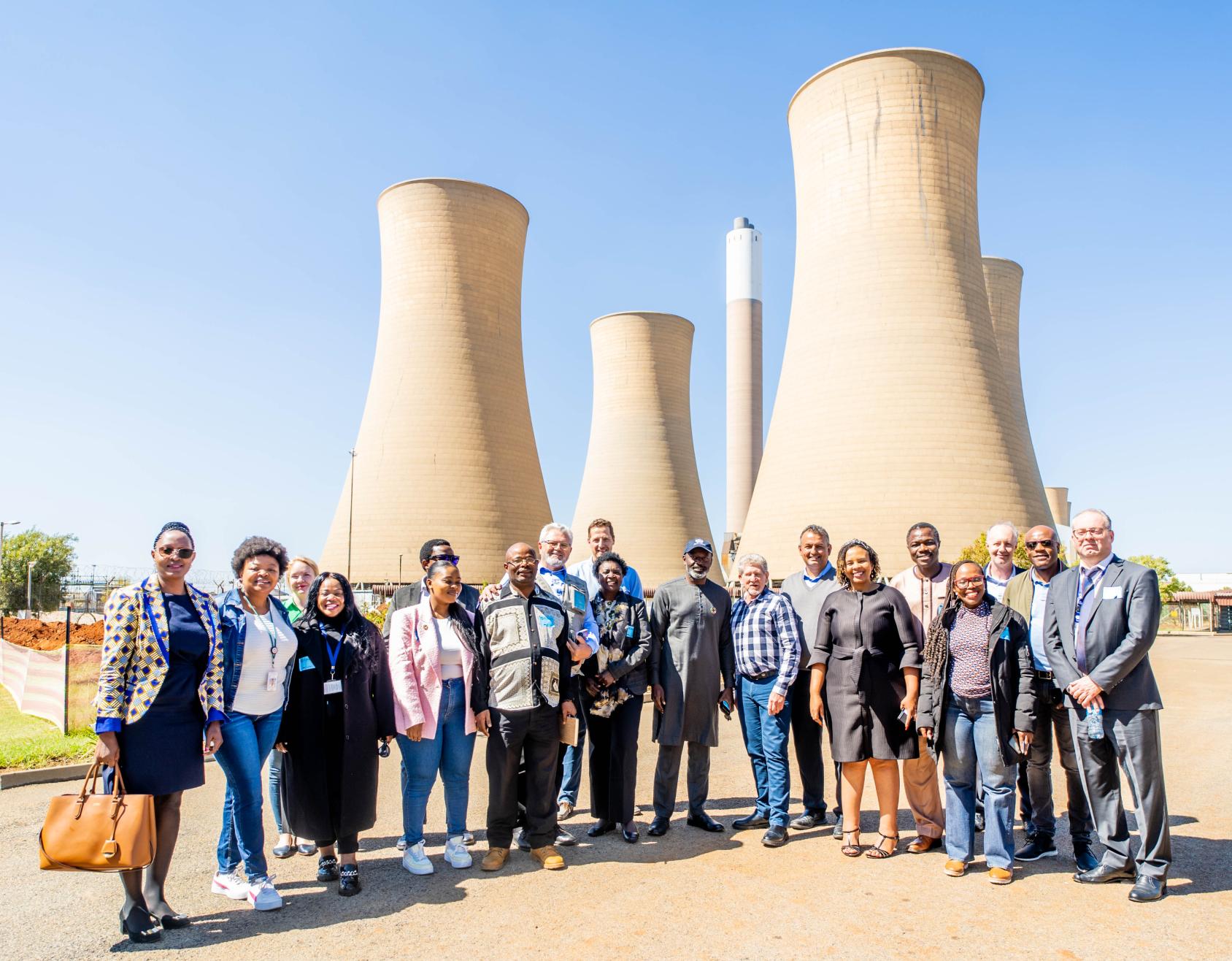 A group of people stand outdoors in a renewable energy facility 