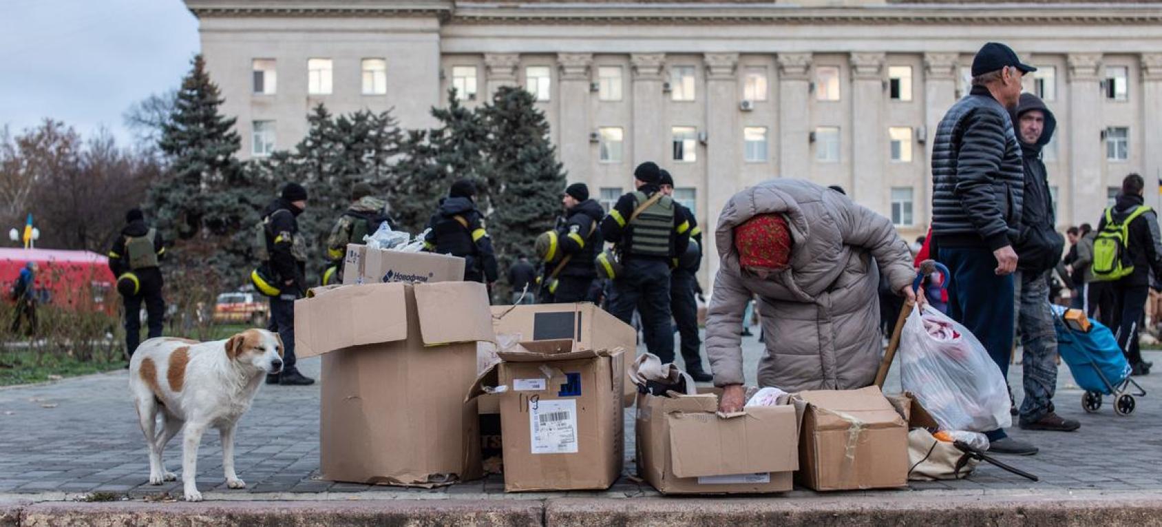 A person in winter clothes is picking things out of boxes in an outdoor space
