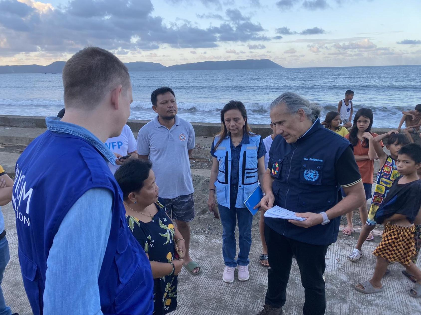 UN Resident and Humanitarian Coordinator in the Philippines speaking to a group of people including children on a beach