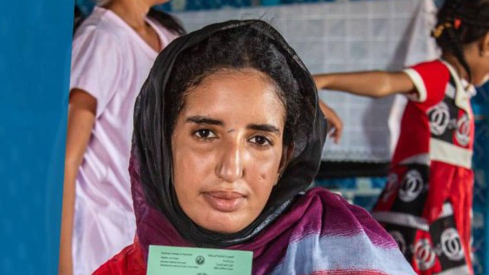 A woman holding a voter registration card