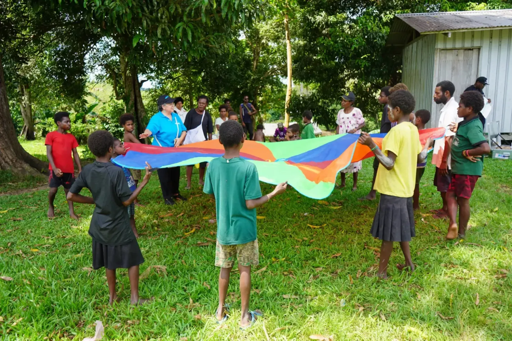 A group of children in a garden playing with a colourful tarp