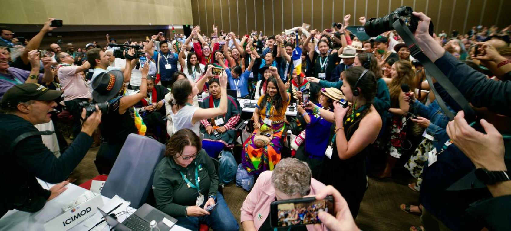 A group of people celebrating and taking pictures in an indoor conference room