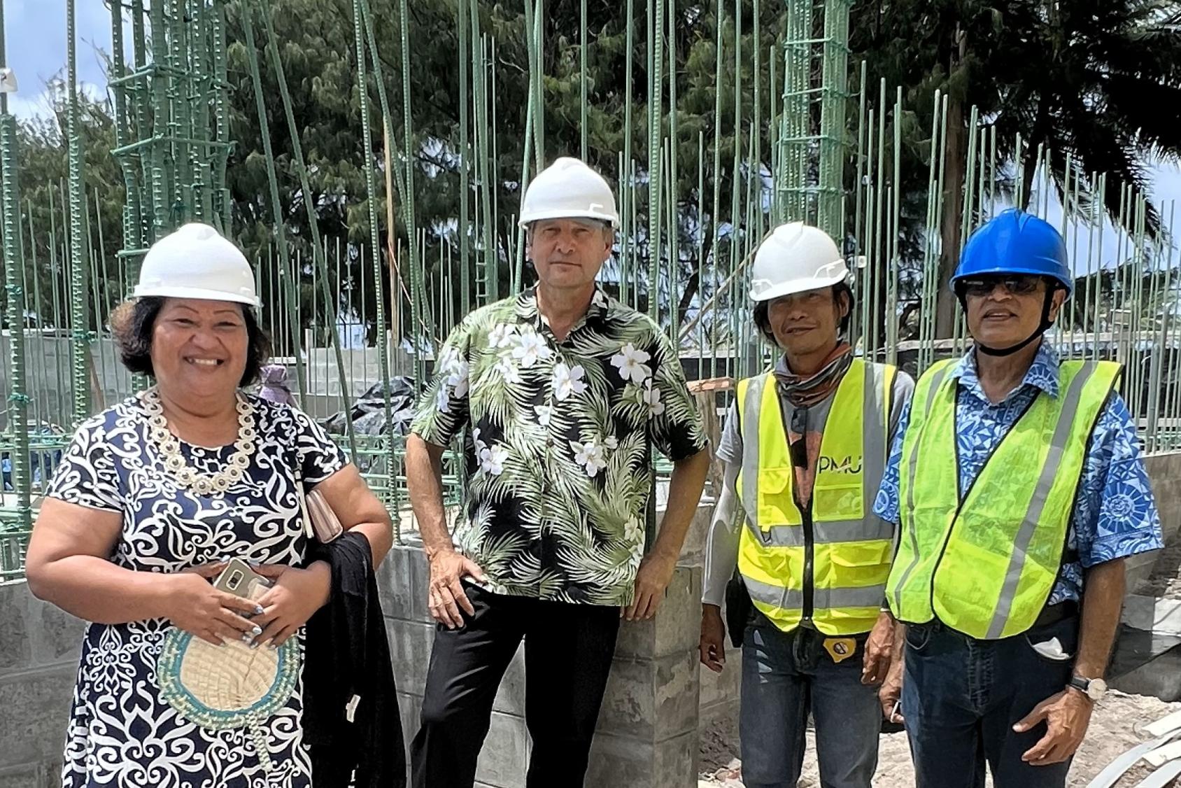 A group of UN agency representatives wearing hard hats in an outdoor space