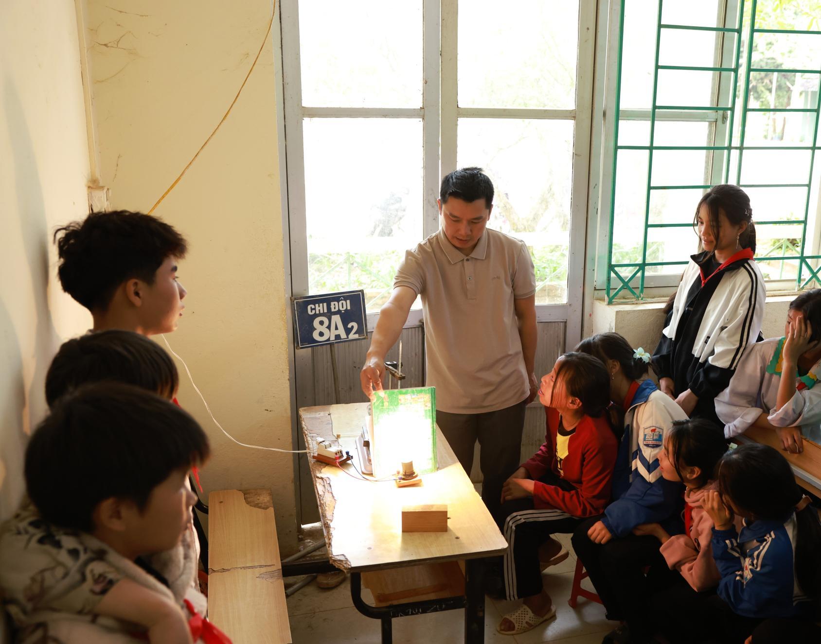 A group of students in a classroom watching a demonstration from a teacher