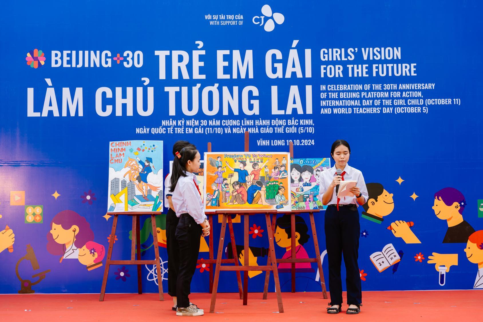 A group of young girls on a stage with an exhibit between them