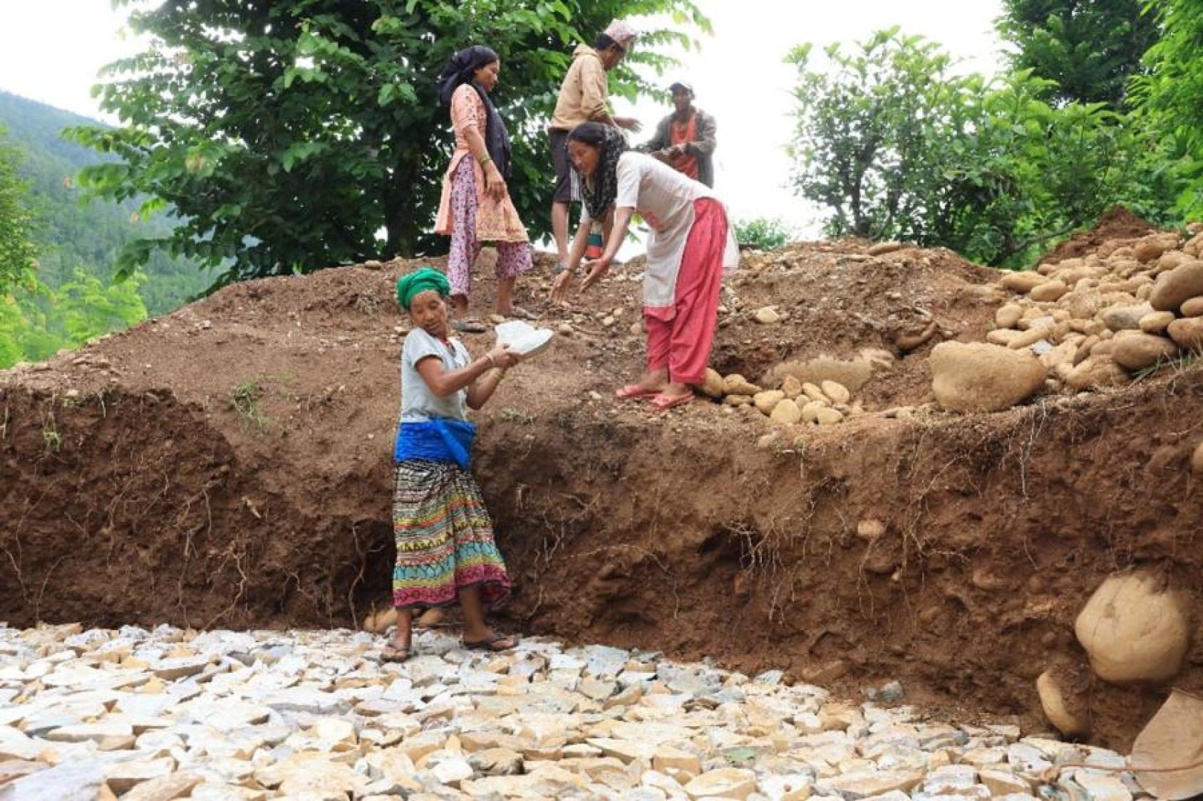 A group of people building in an outdoors space, mostly women 