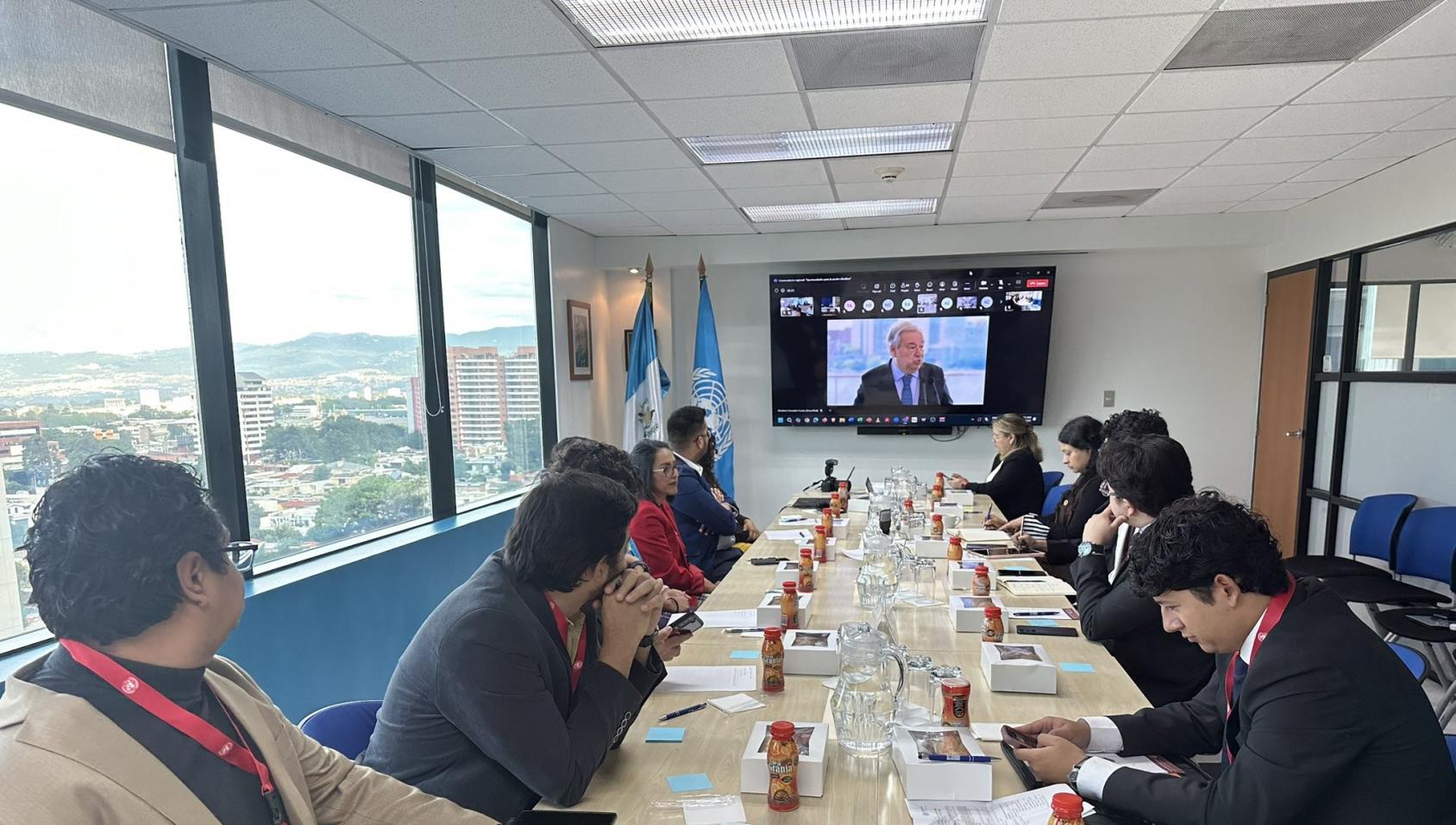 A group of young people around a table watching the SG on a screen