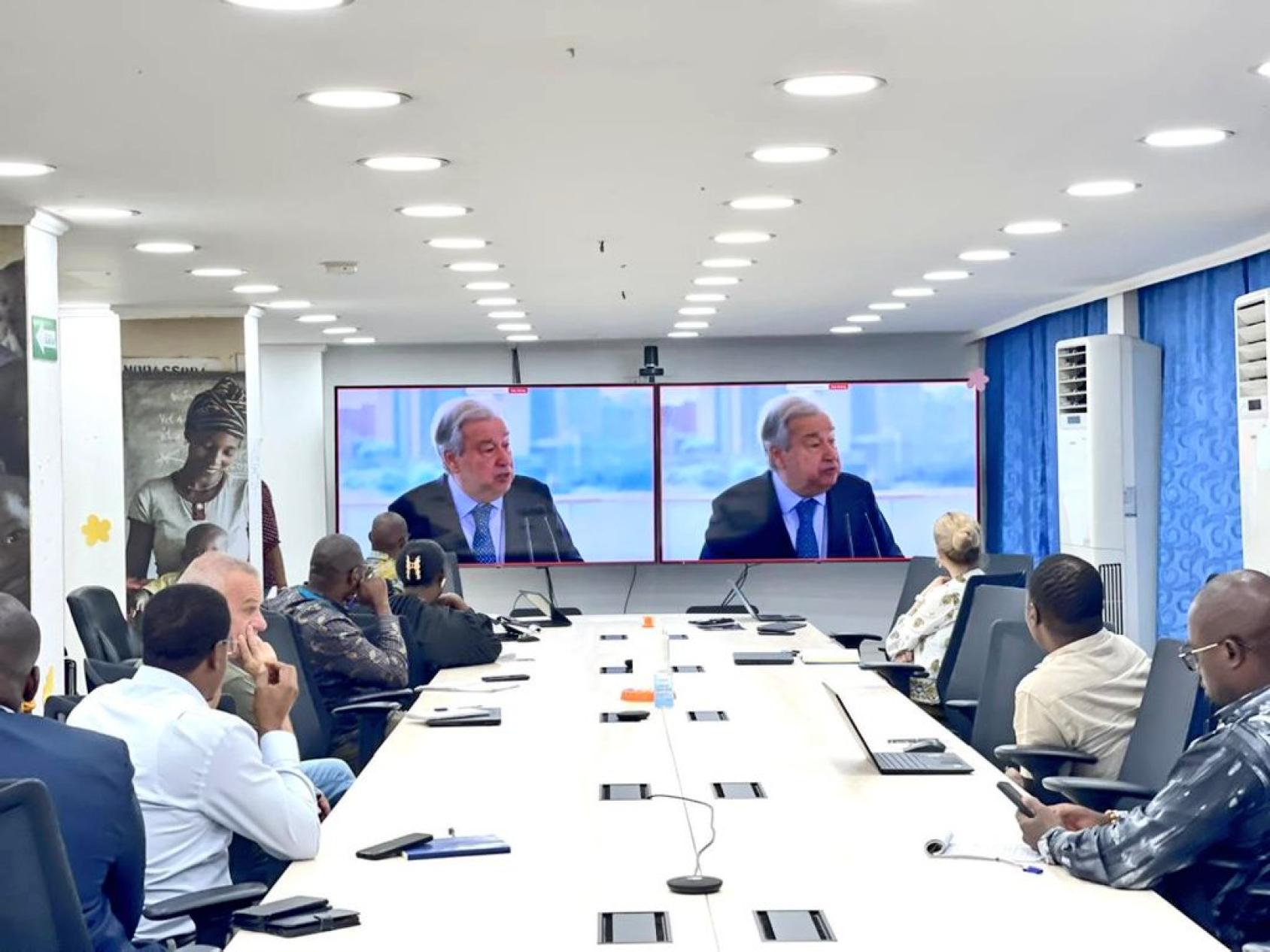 a group of people watching the SG on a screen