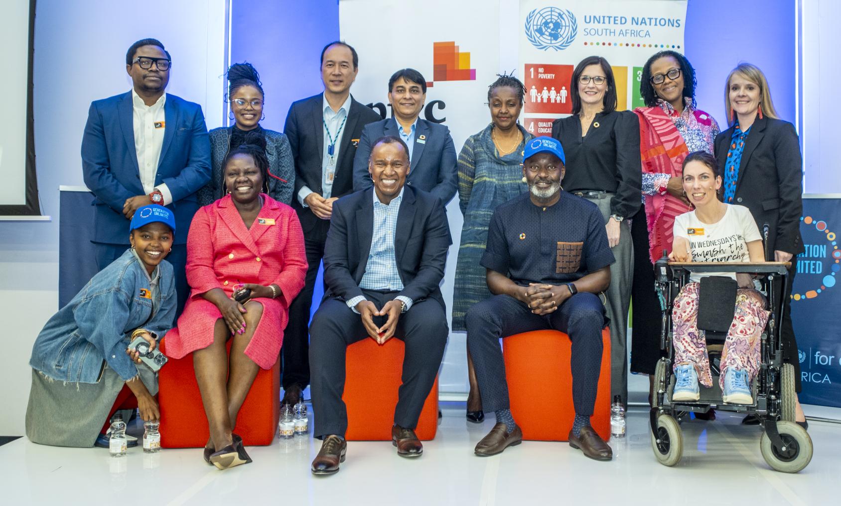 A group of people standing in front of UN branding and smiling at the camera