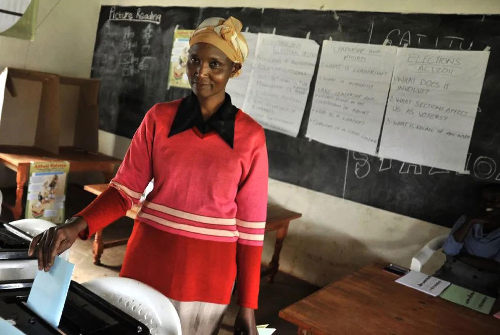 A woman casting her vote in a classroom