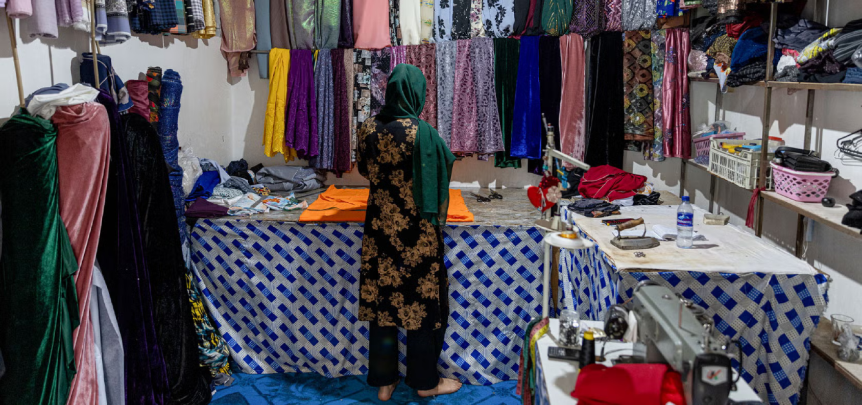 A woman turning her back to the camera in front of some materials 