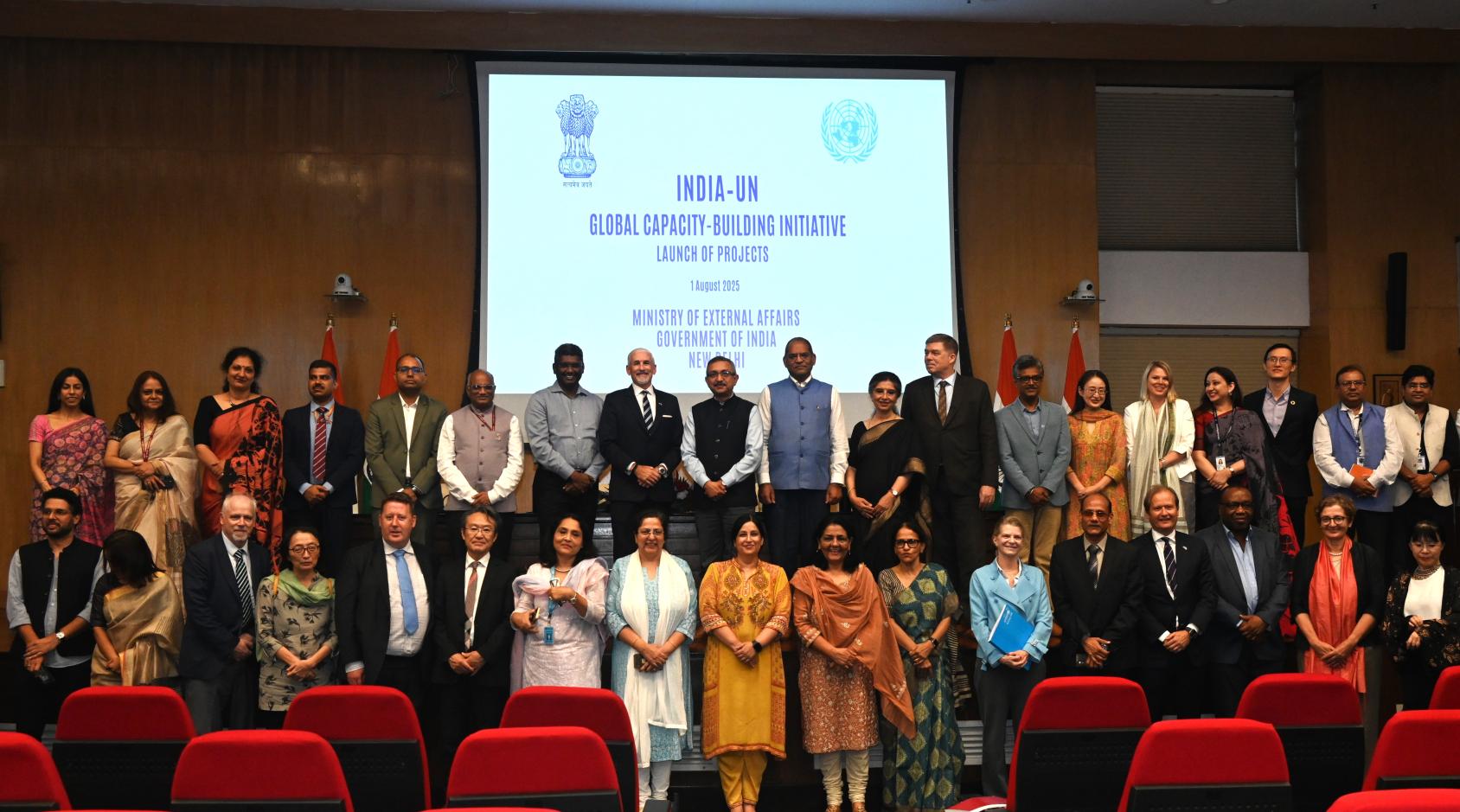 A group of people in an indoor setting with the UN-India capacity building initiative on a banner behind them