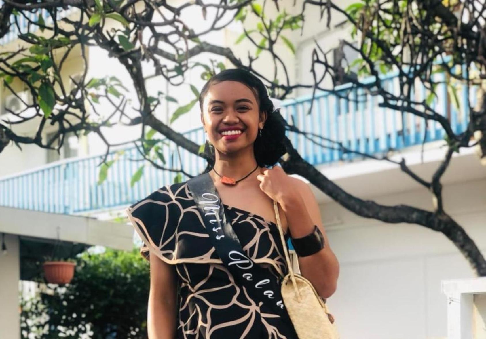 A young woman in an outdoor setting. She is smiling and looking at the camera