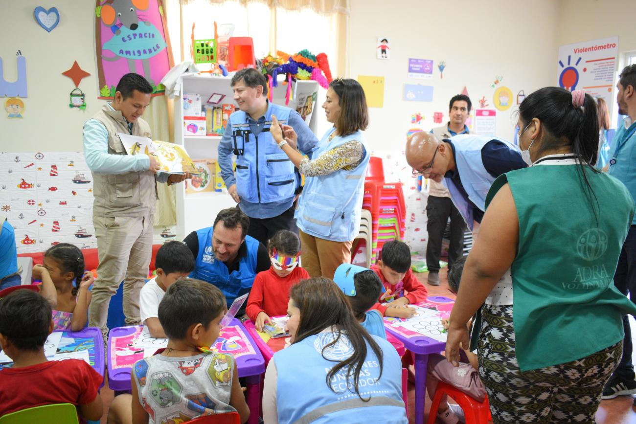 Women stands in a classroom with children taking a photo of a book 