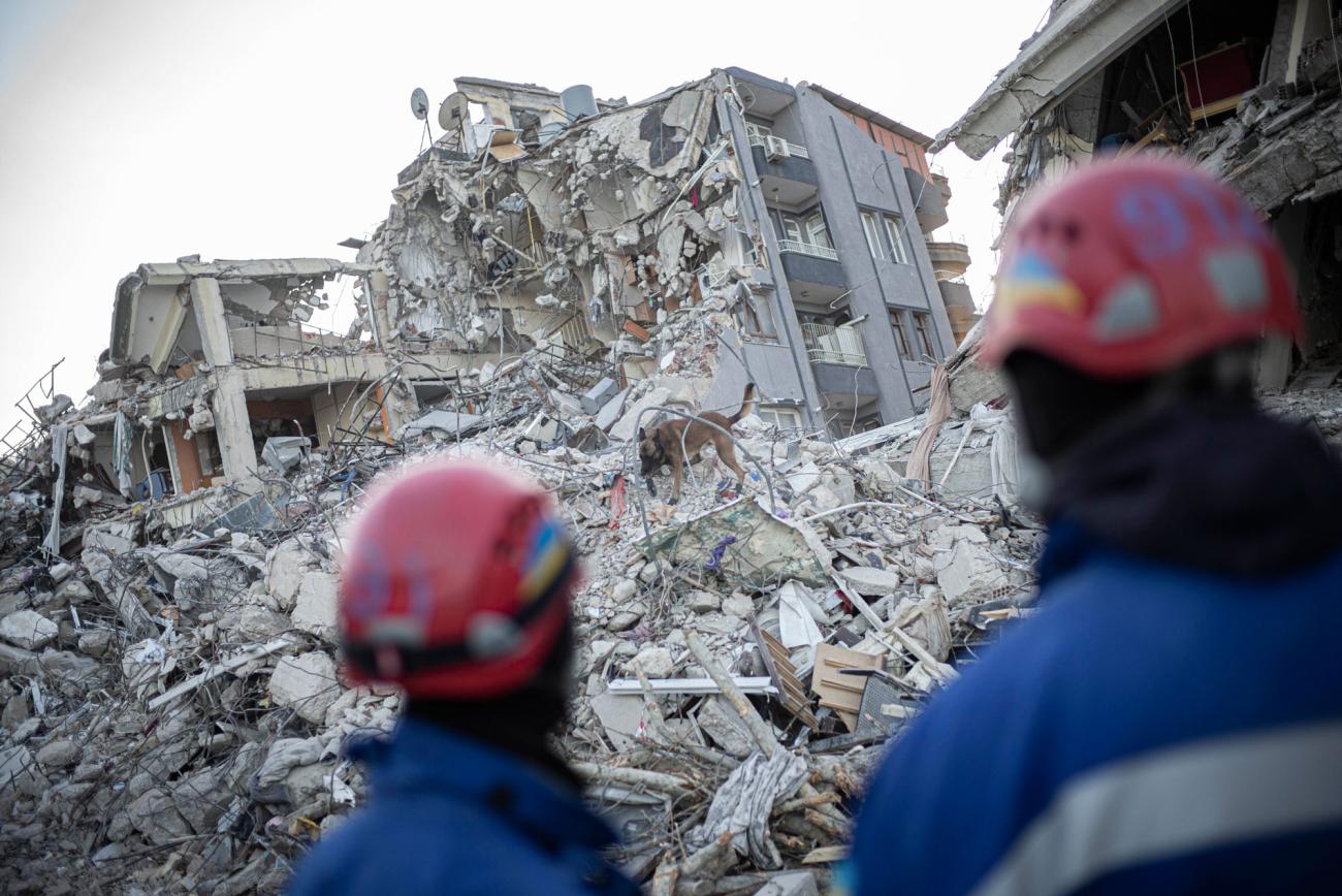 Two rescue workers look onto a destroyed building