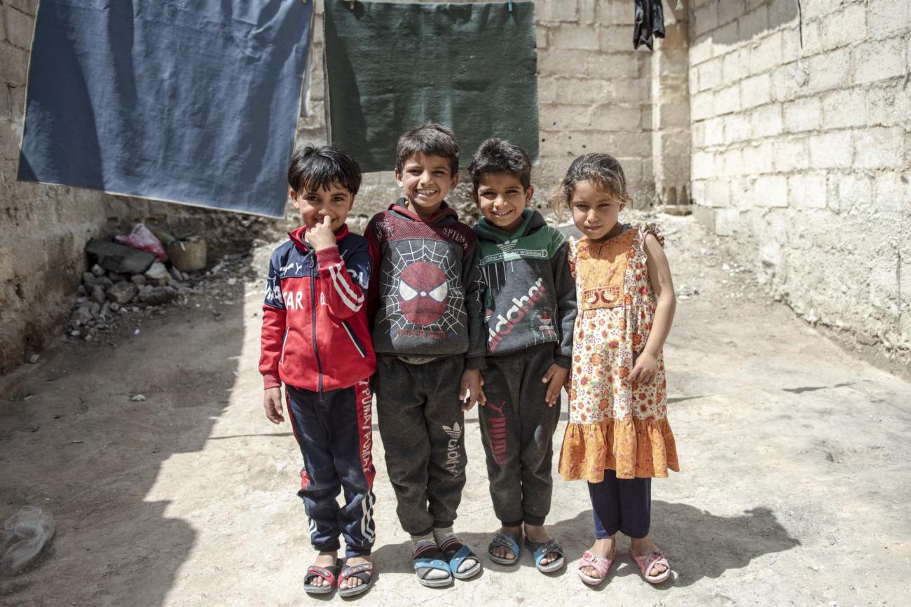 Group of four children stand together smiling 