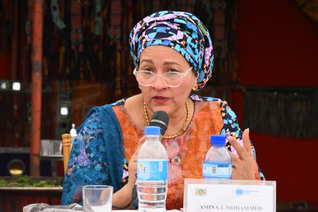 women in colourful headscarf speaks into microphone 