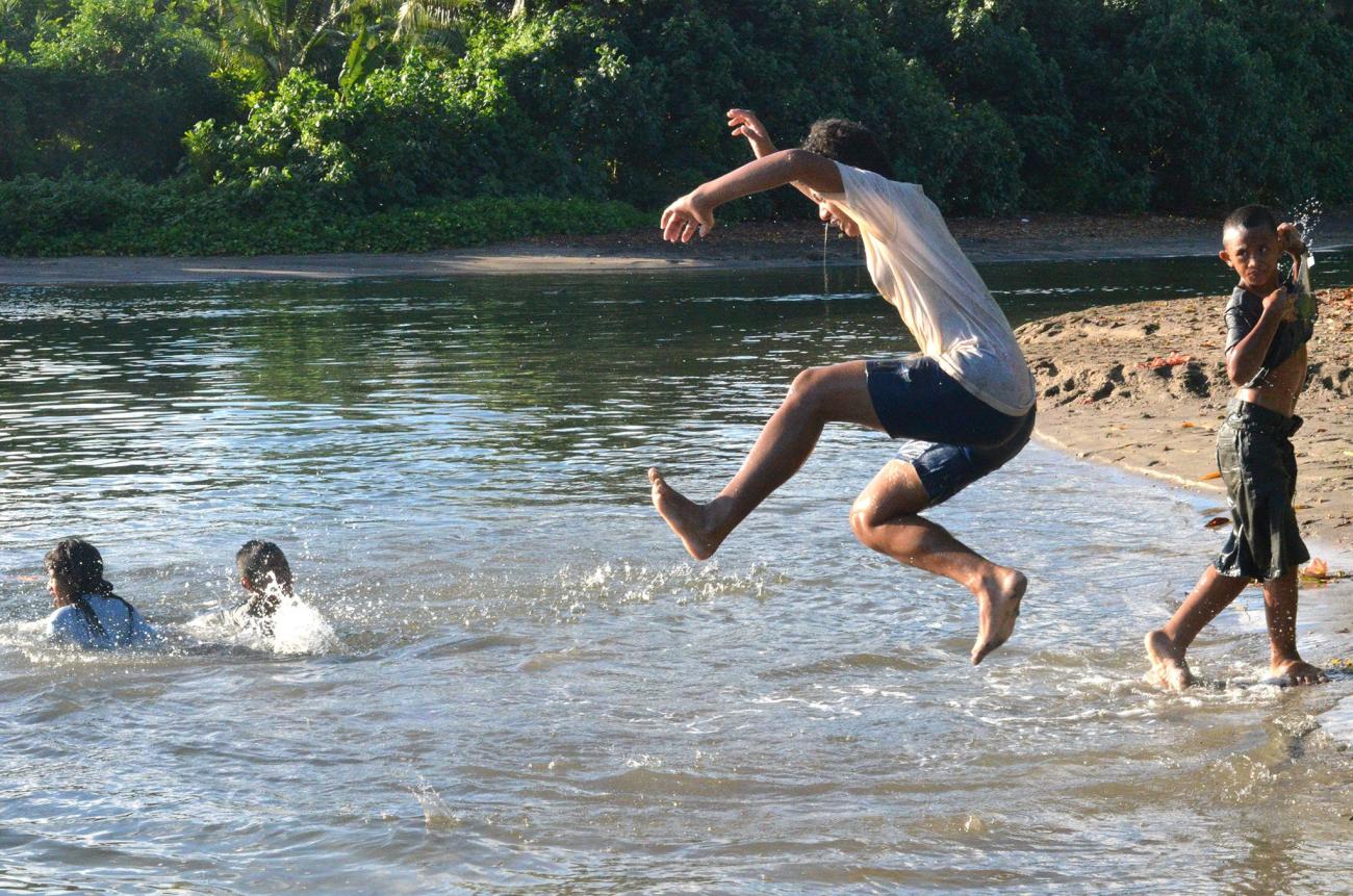 young boys jump into a river 