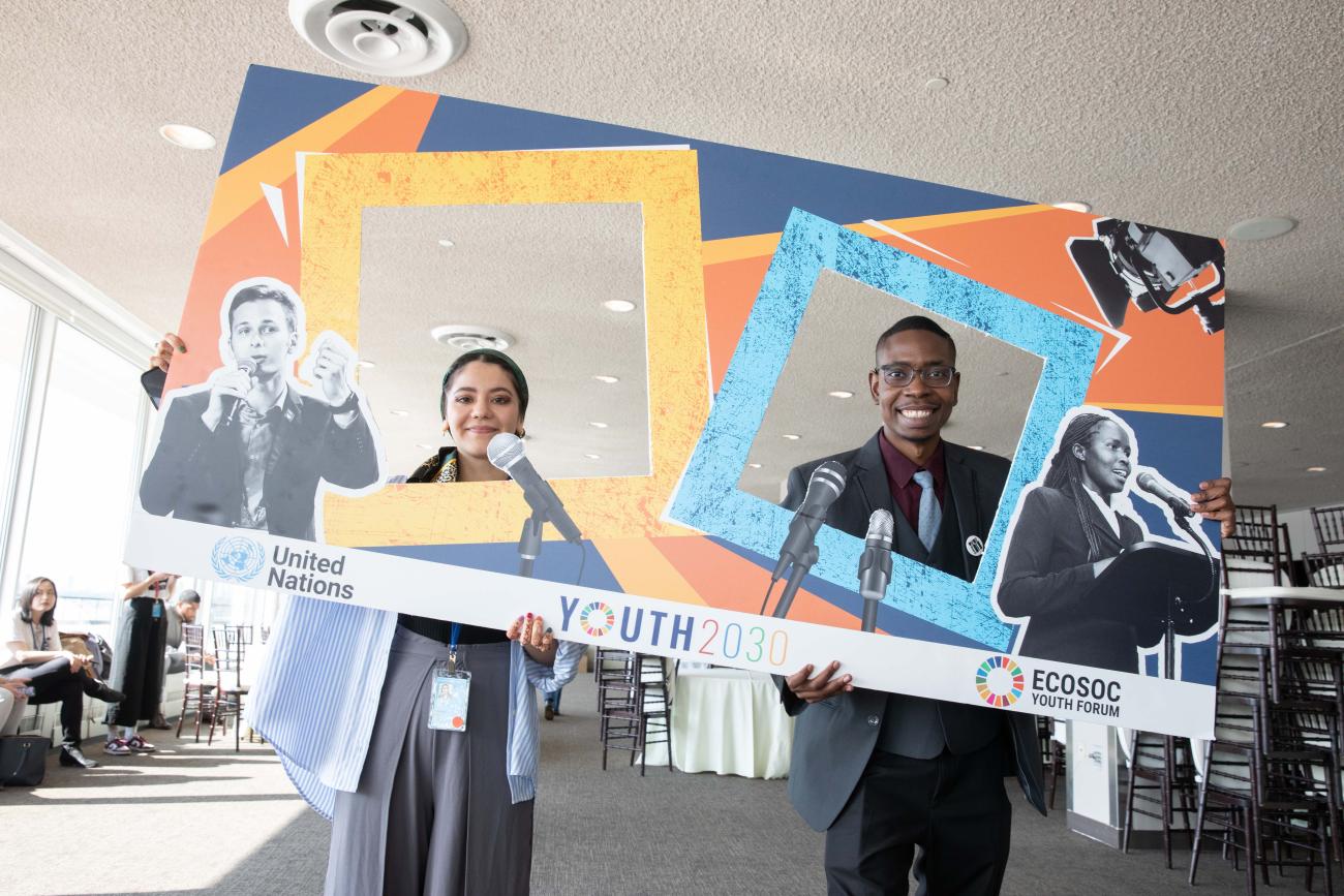 a young man and woman stand posing with posters 