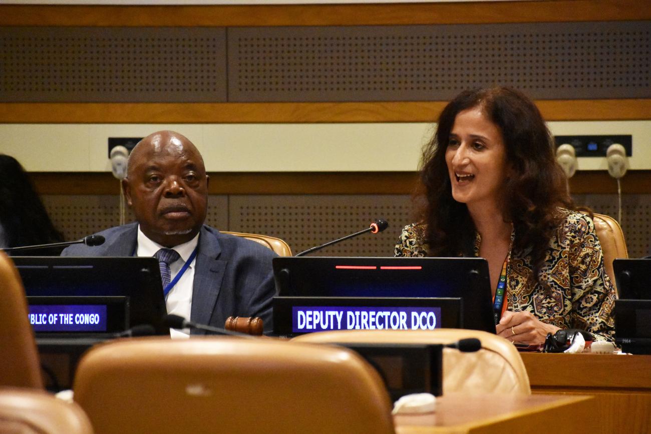 man in dark suit sits next to woman with long dark hair at panel event 