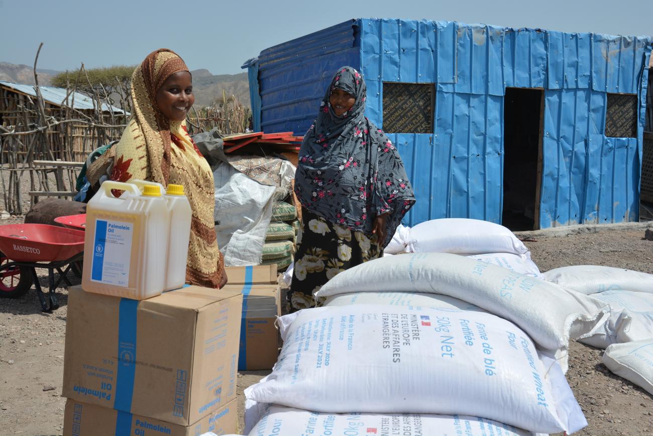 a woman and man stand with boxes and sacks of food