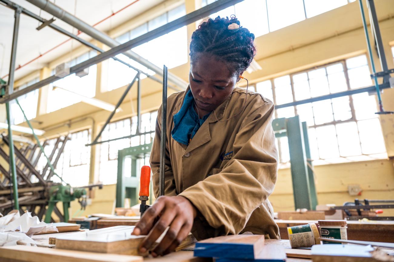 woman in beige jacket works in carpentry studio  