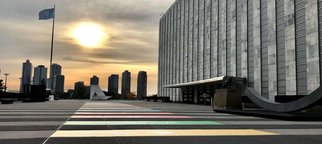 grey building with the sun rising over city skyline in the background 