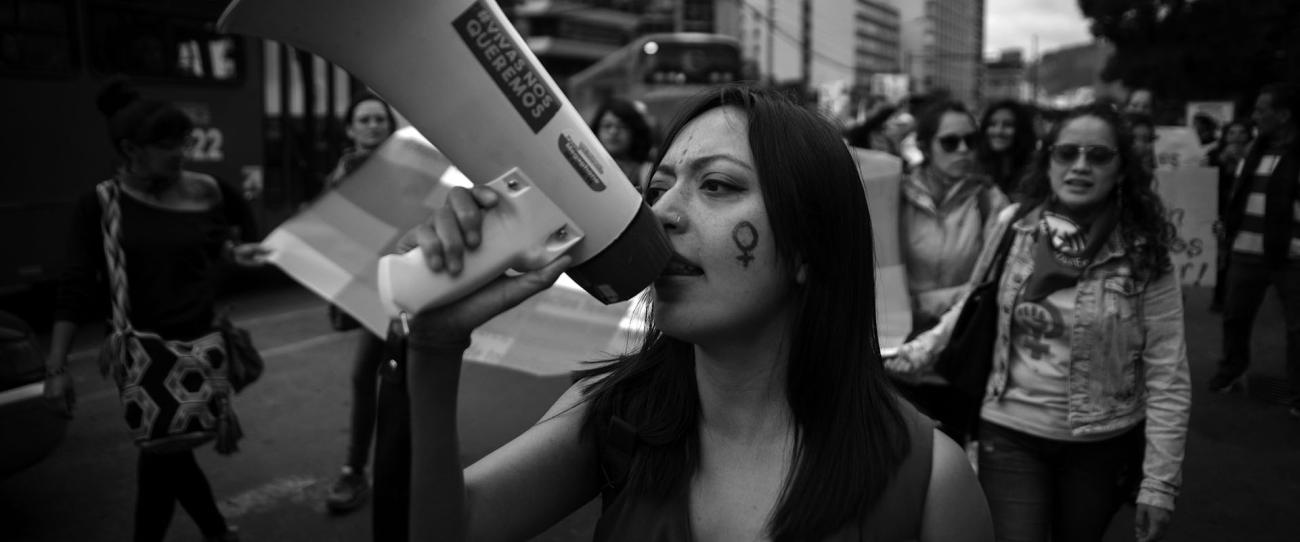 black and white photo of woman at protest speaking into a megaphone