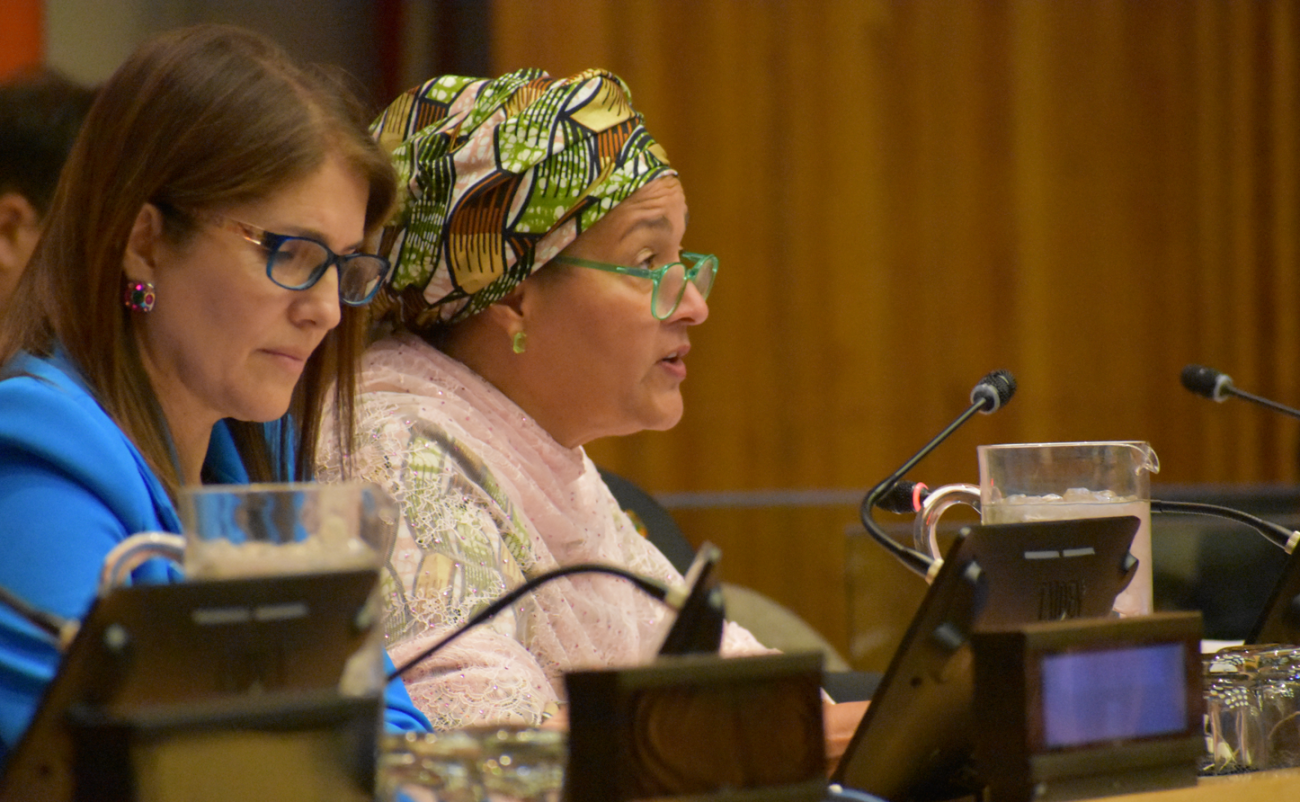 woman in pink top and green head scarf speak at panel discussion
